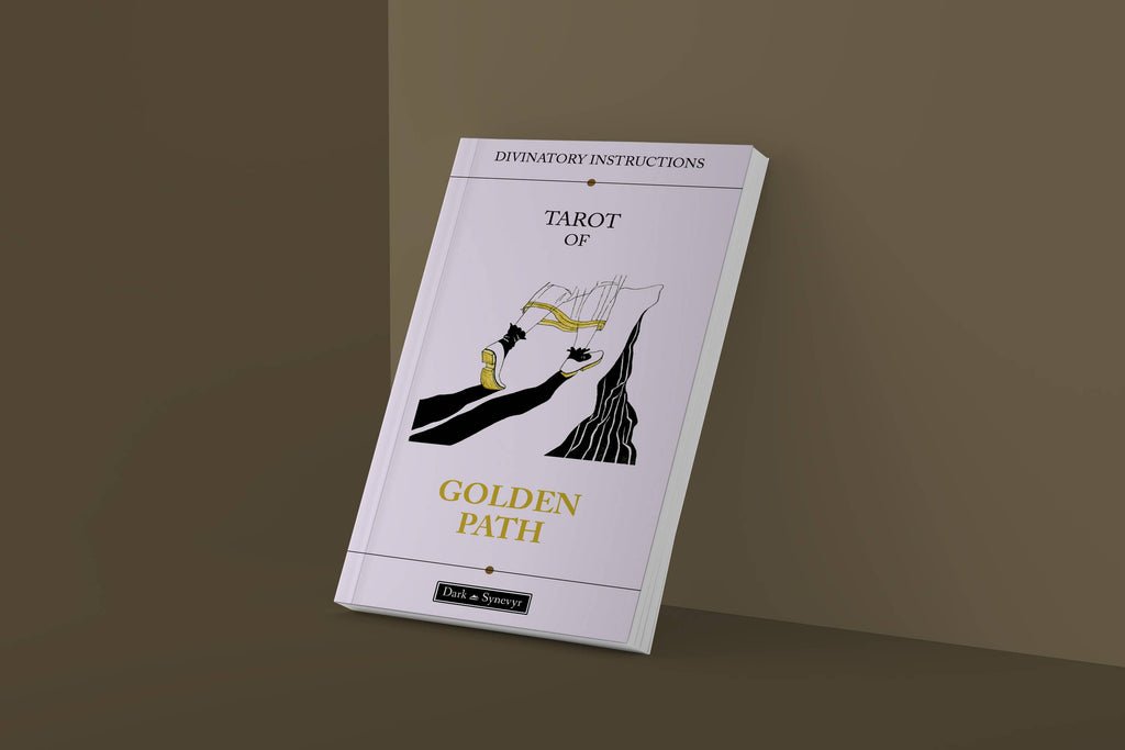 The Golden Path Tarot guidebook standing upright against brown background